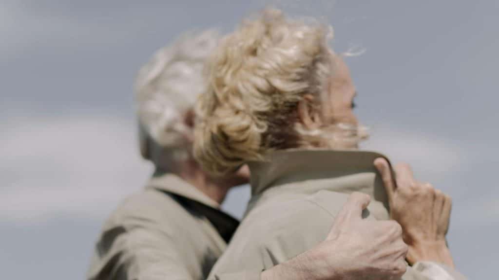 A senior couple embracing outdoors on a windy day.