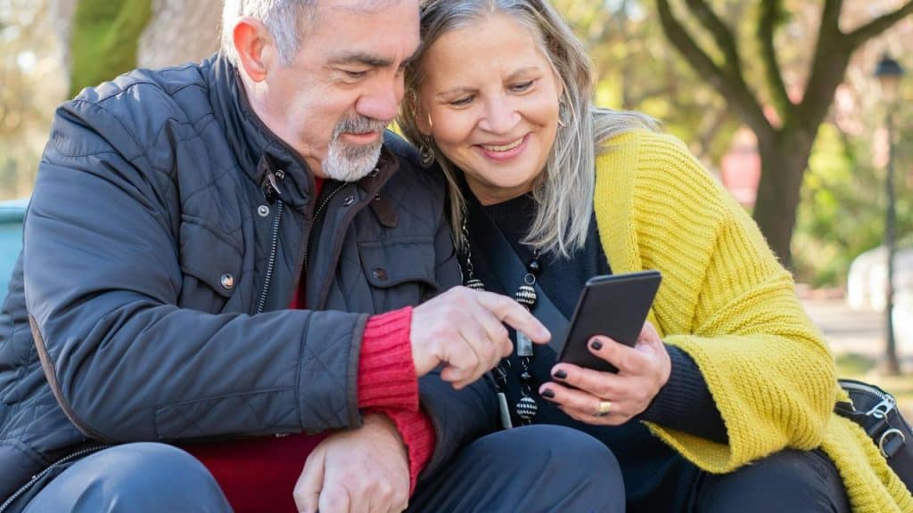 A senior couple sitting together looking at a smartphone.