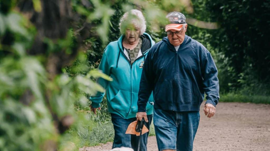 A senior couple walking together on a wooded path.
