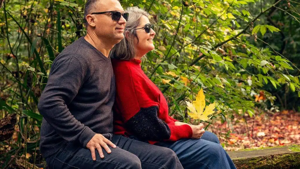 A couple sitting together outdoors holding a leaf.