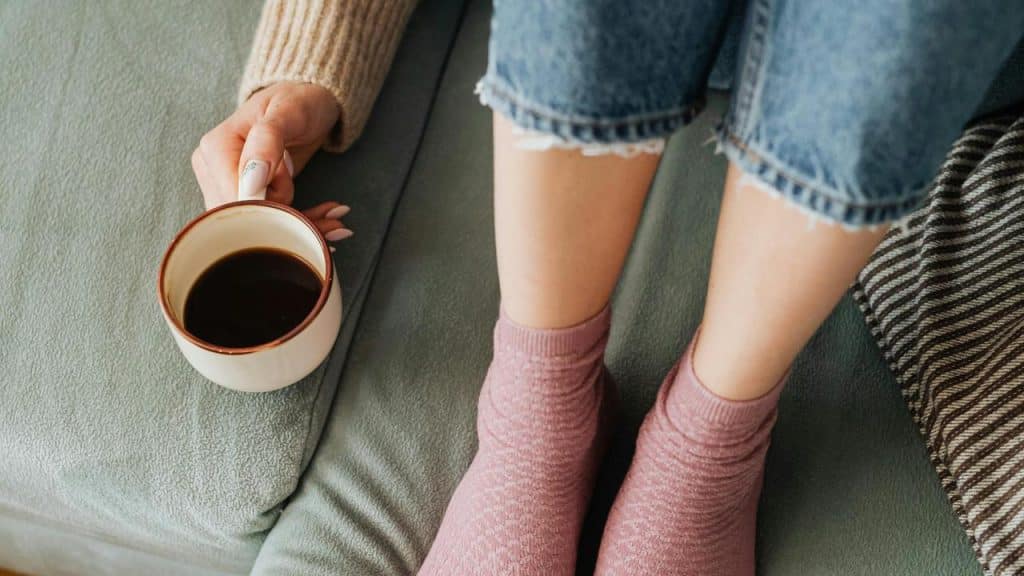 A person sitting on a couch holding a cup of coffee.