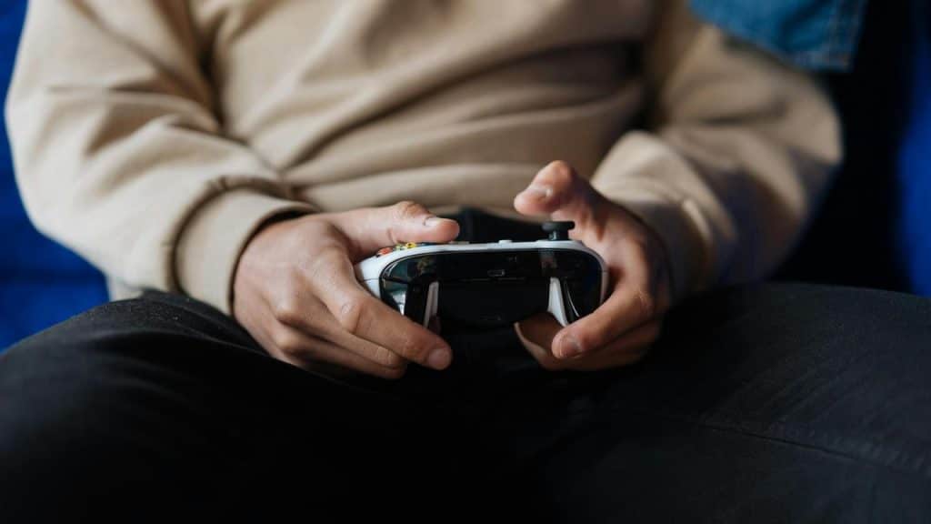A person holding a video game controller while sitting down.