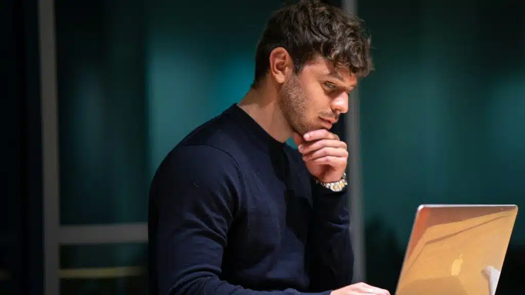 A man thinking while using his laptop.