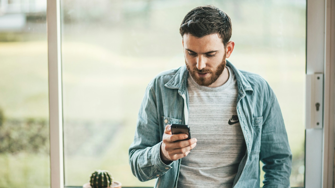 A bearded man using his phone.