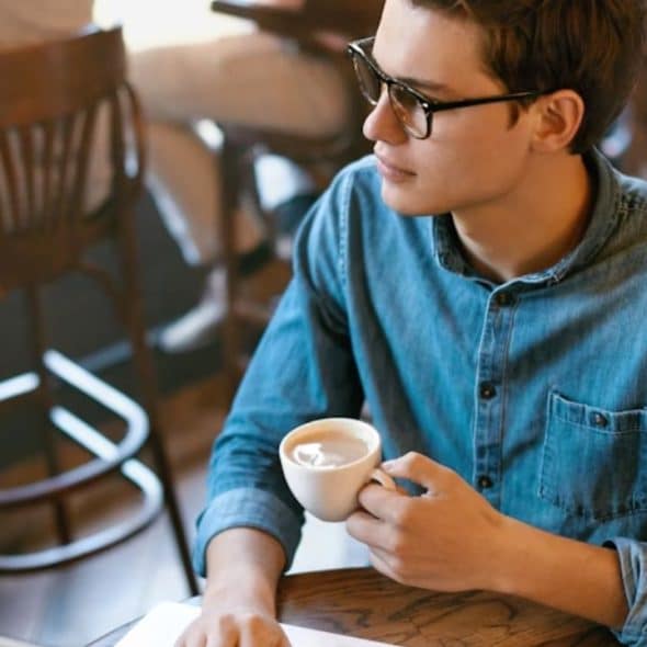 A man sitting thoughtfully while holding a coffee cup
