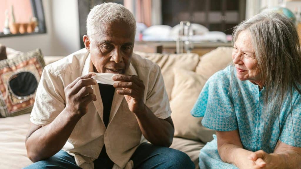 An elderly man holding a tissue while an elderly woman smiles at him.
