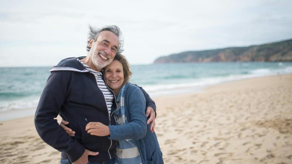 A happy couple hugging on a sandy beach.
