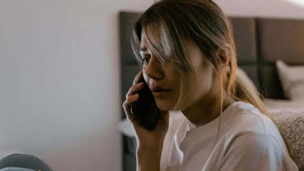 A woman sitting on a bed talking on the phone.