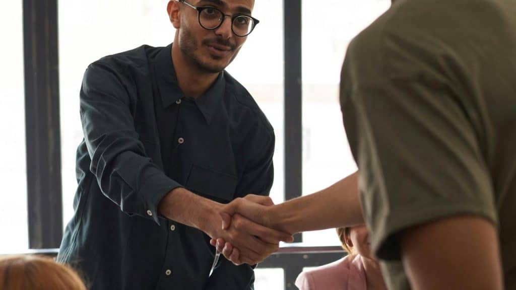 A man shaking hands with another person in an office setting.