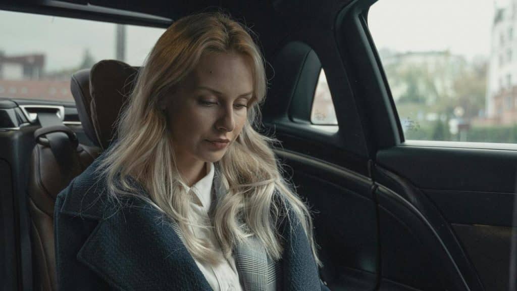 A woman sitting in the back seat of a car looking down.