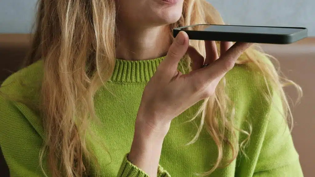 A woman speaking into a smartphone.