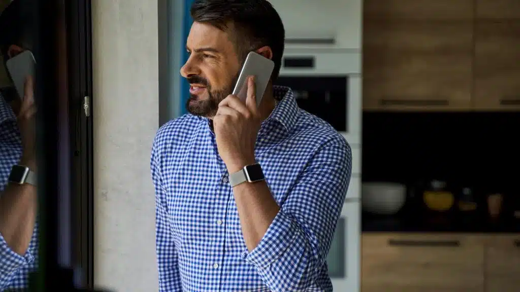 A man talking on a smartphone by a window.