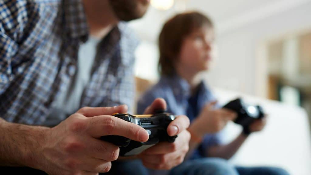 A man and a child playing video games with controllers.