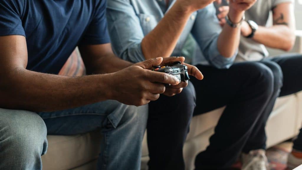 A group of friends playing video games on the couch.