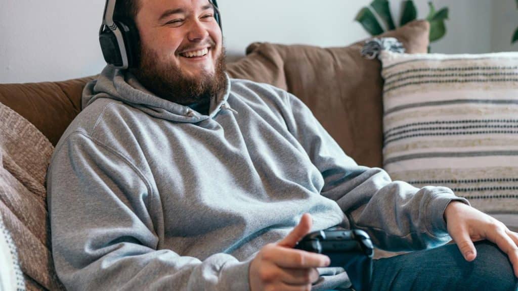 A man smiling while playing video games with headphones on.
