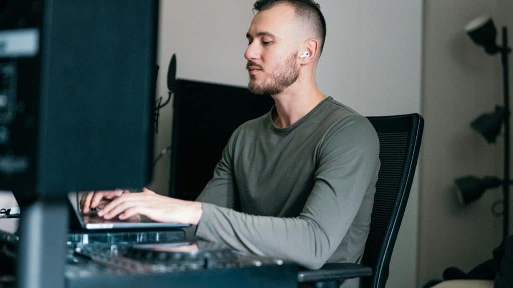 A man working on a computer with earbuds in.