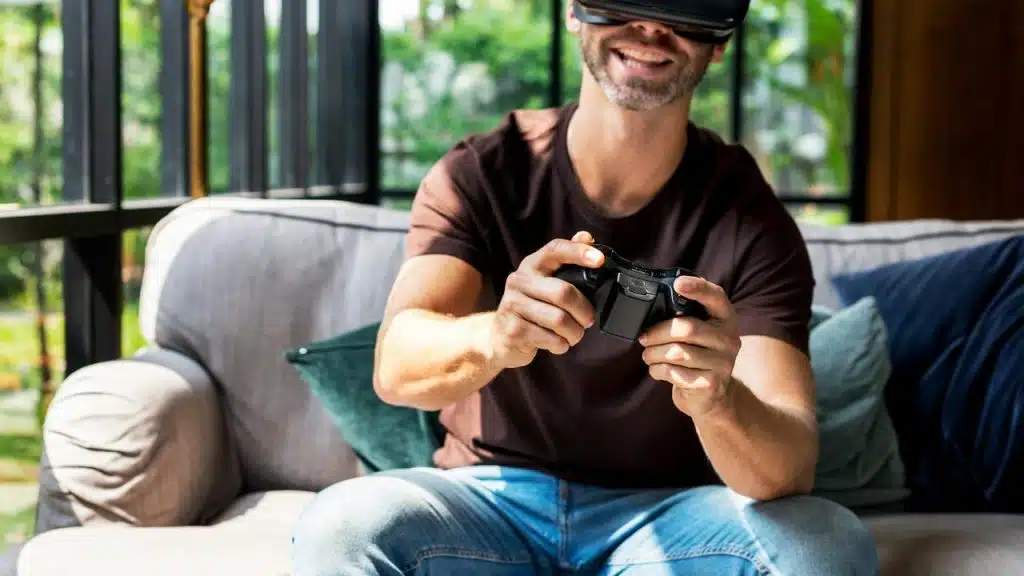 A man playing video games with a VR headset and controller on the couch.
