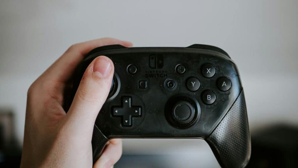 A person’s hand holding a Nintendo Switch controller.