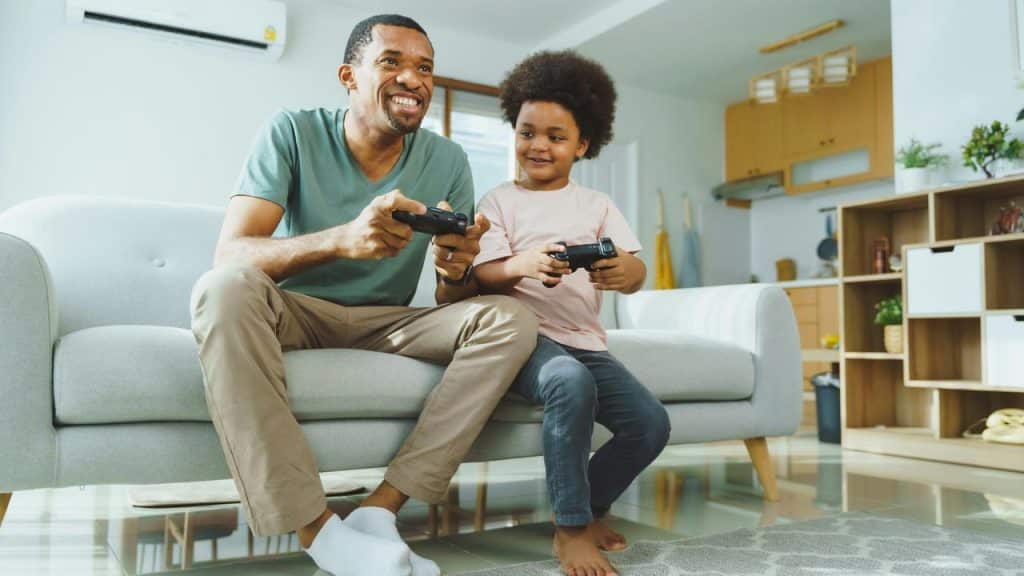 A father and child playing video games together in the living room.