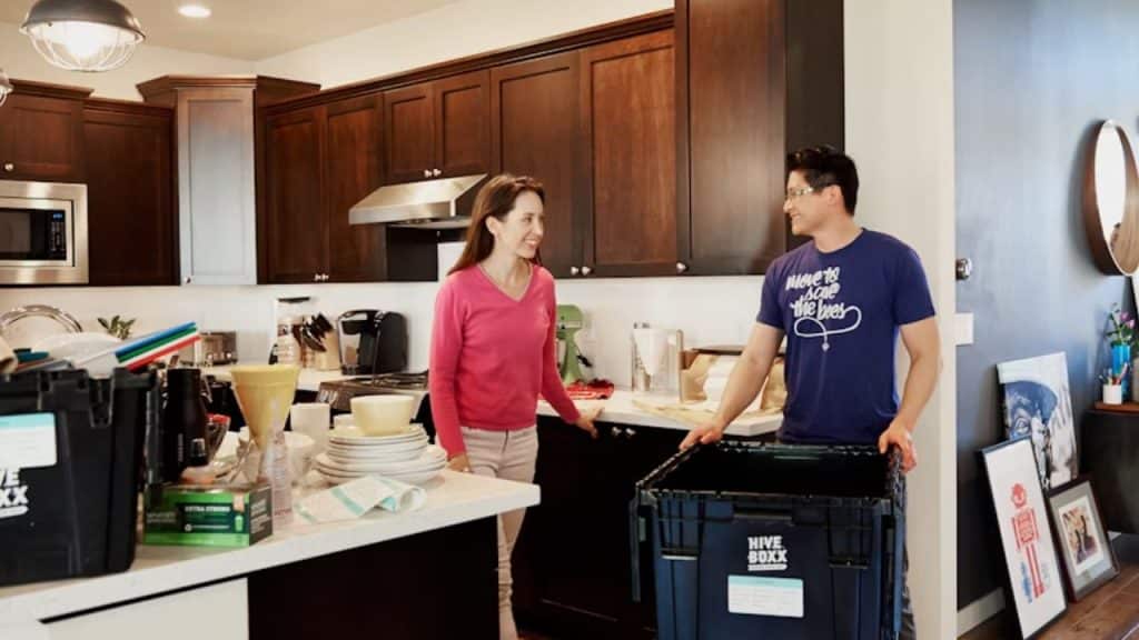 Husband lifting a heavy box while wife smiles at him