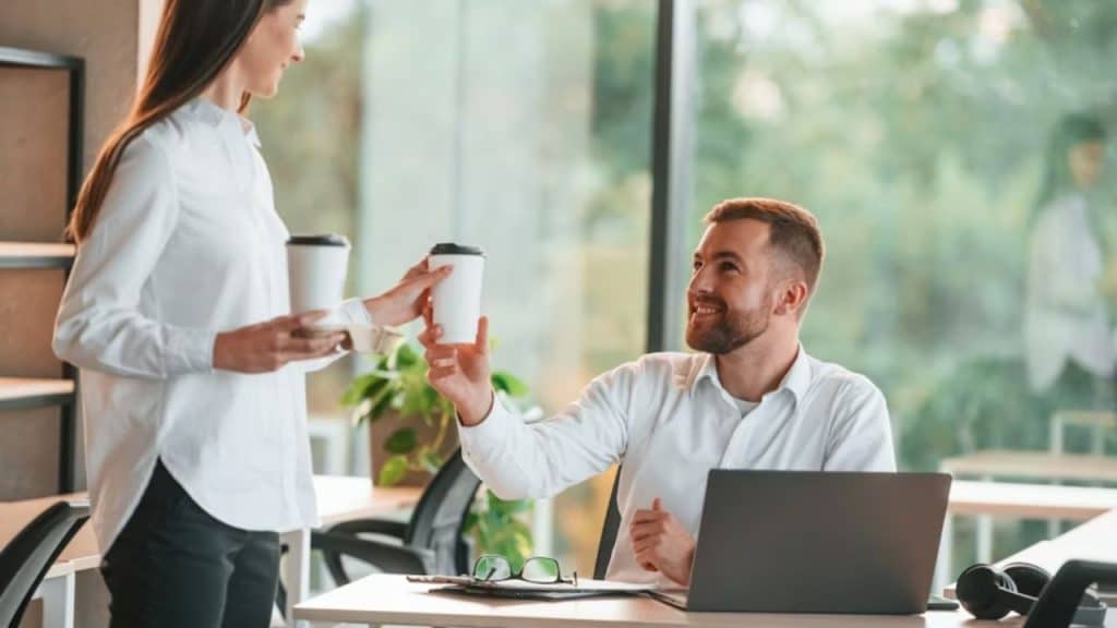 Husband working at desk while partner brings him coffee