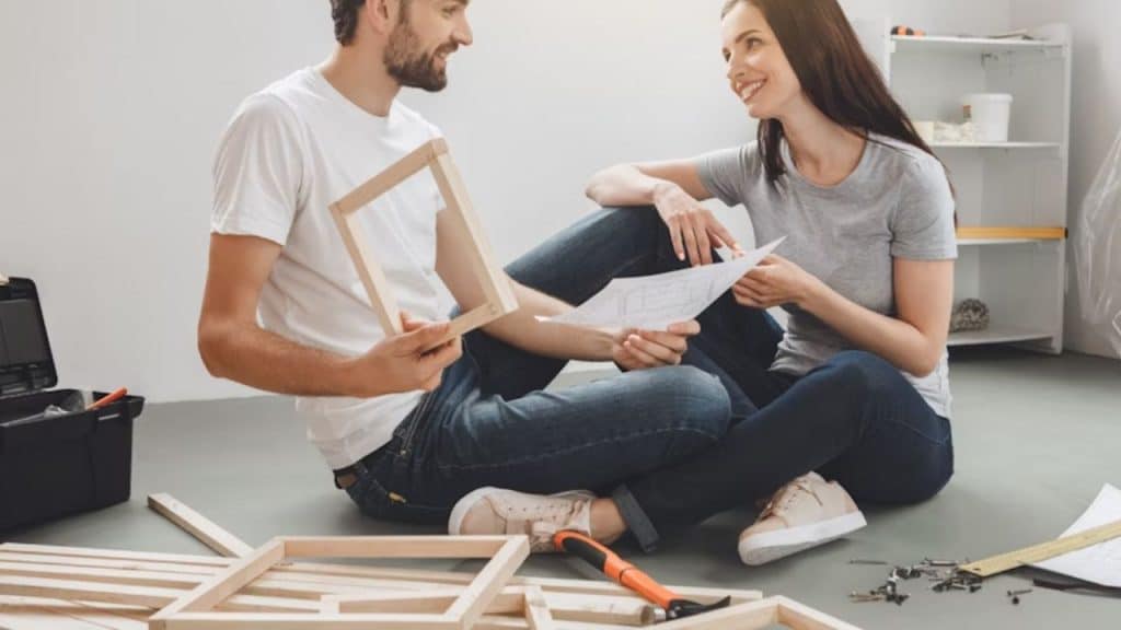 Man fixing something in the house while his partner looks impressed