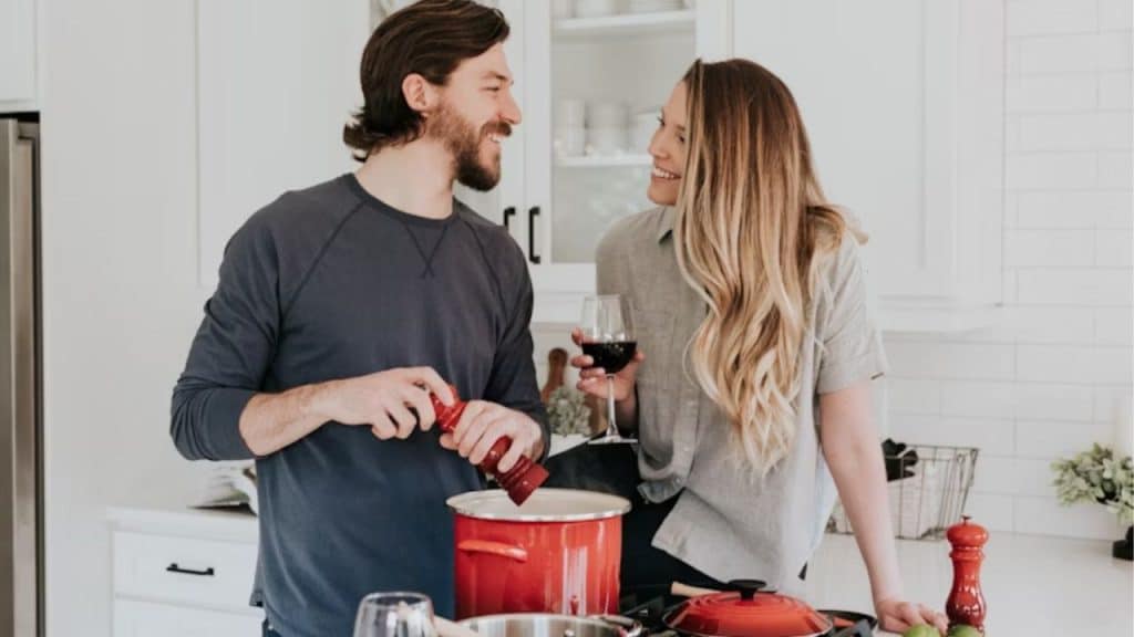 Husband cooking dinner while smiling at his partner