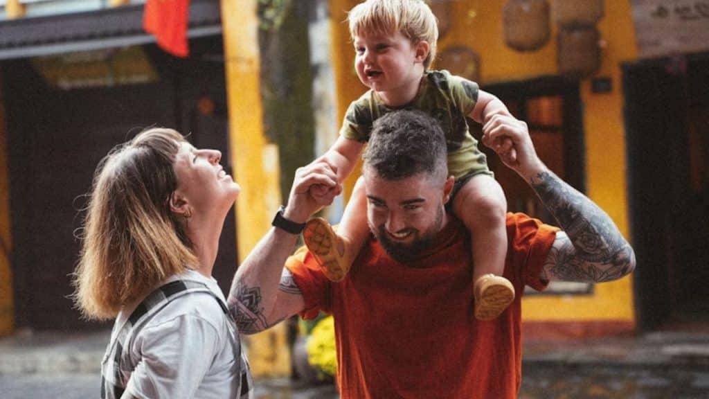 Husband playing with kids while partner smiles