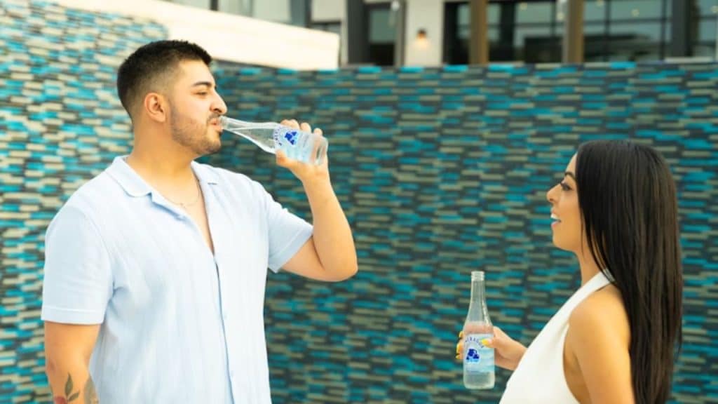 Man drinking water after exercise with his partner nearby