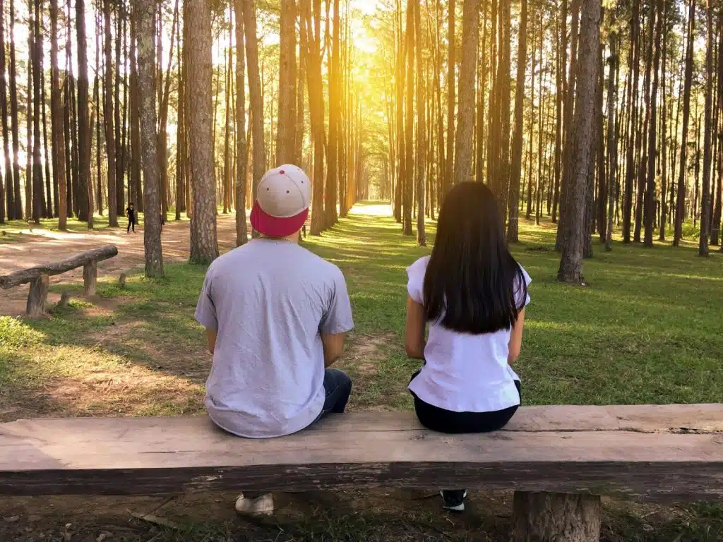 A man and woman sitting at the wooden bench