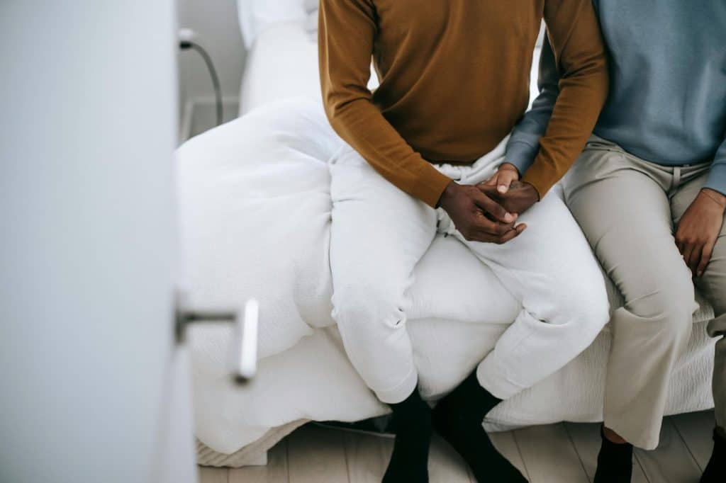 A man and woman sitting at the bed
