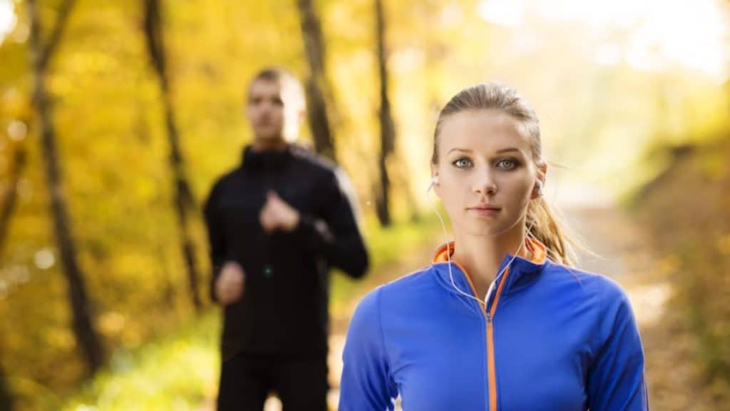 A couple jogging together, the man lagging behind and looking tired