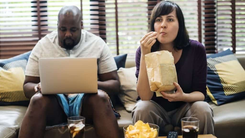 Man and woman eating fast food takeout at home looking disengaged