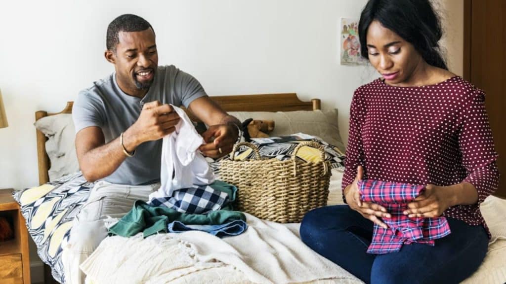A man helping his wife in folding the clothes
