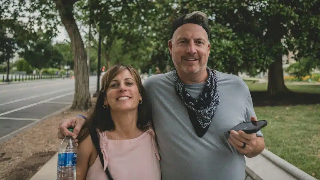 A happy couple with the man holding a water bottle and a smartphone.