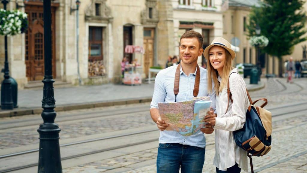 A couple holding a map and smiling while exploring a city together.