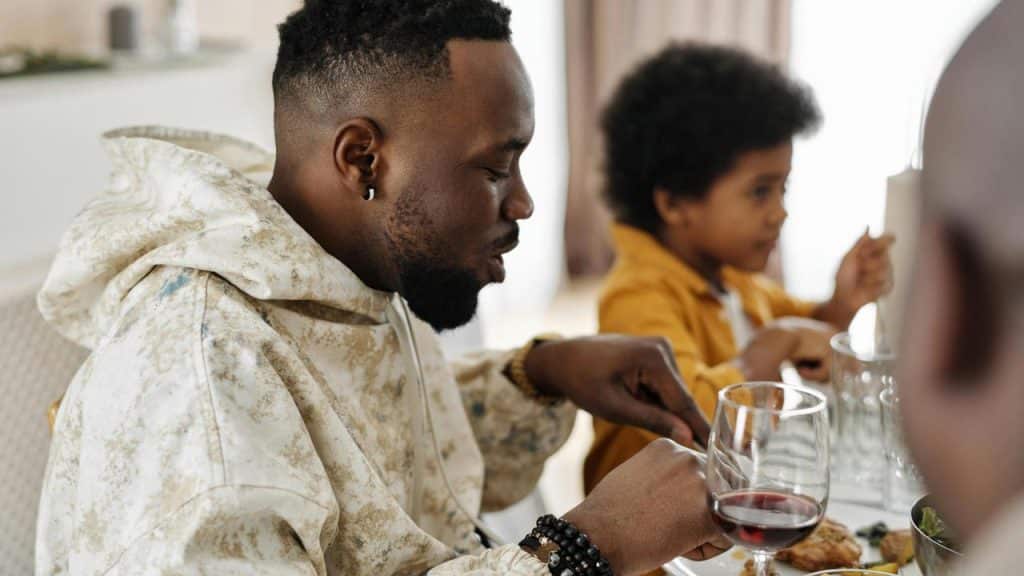 A man eating at a table with a child in the background during a meal.