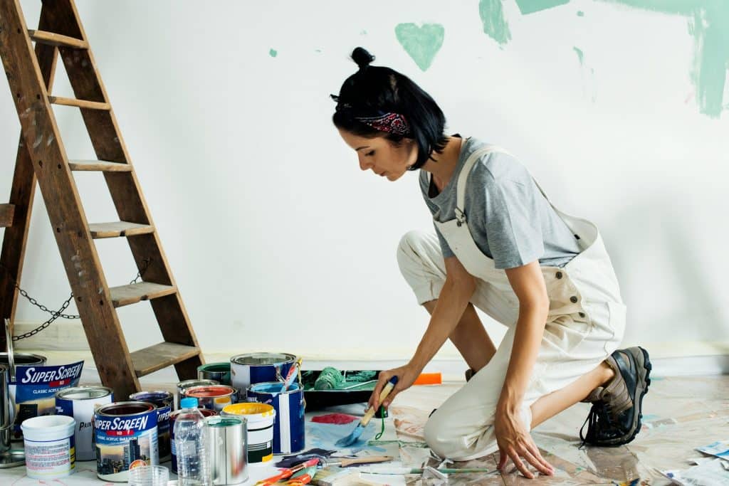 The woman is painting the wall.