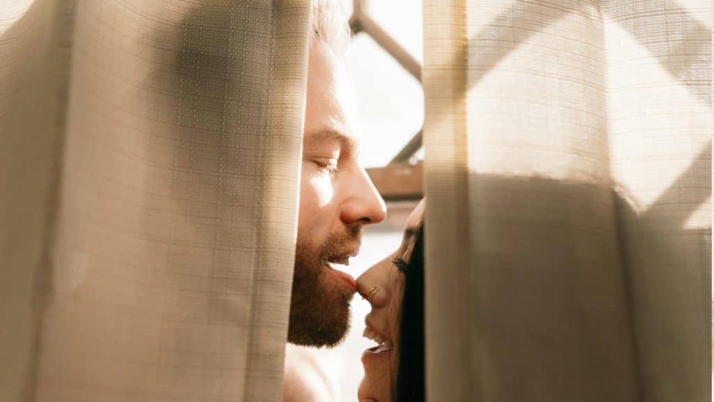 A couple having an intimate moment while hiding behind a curtain.