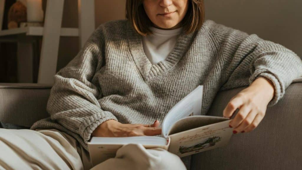 A woman sitting on a couch reading a book.