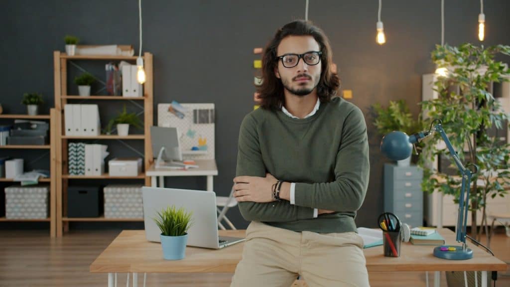 A man with glasses and arms crossed standing in an office.