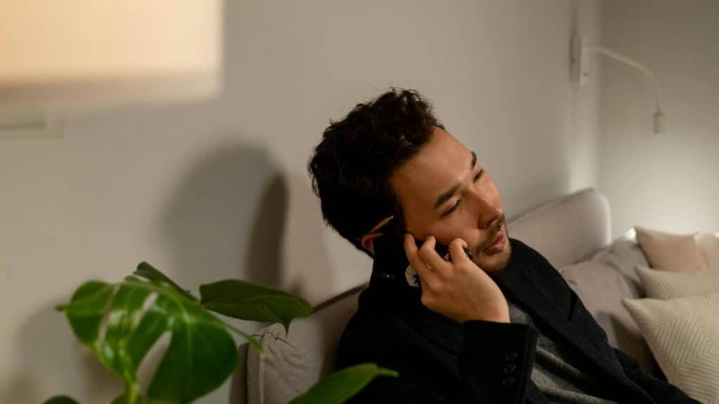 A man sitting on a couch talking on his phone.