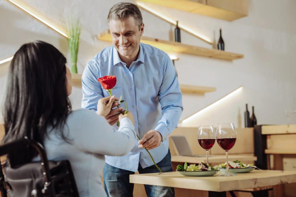 The man is giving a flower to the woman.