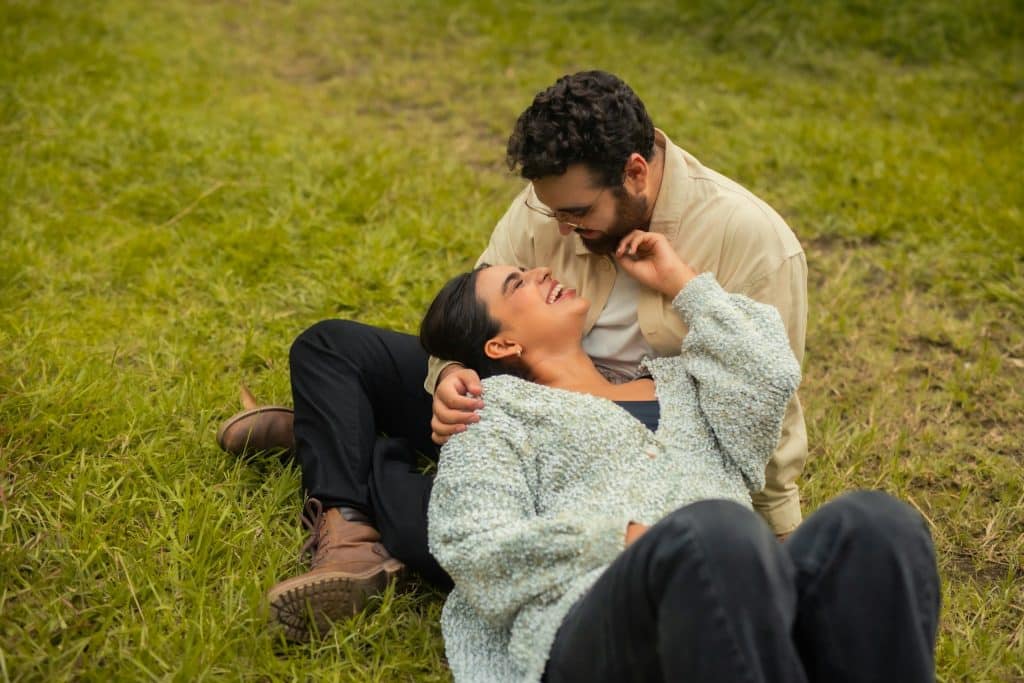 The couple is lying on the grass.