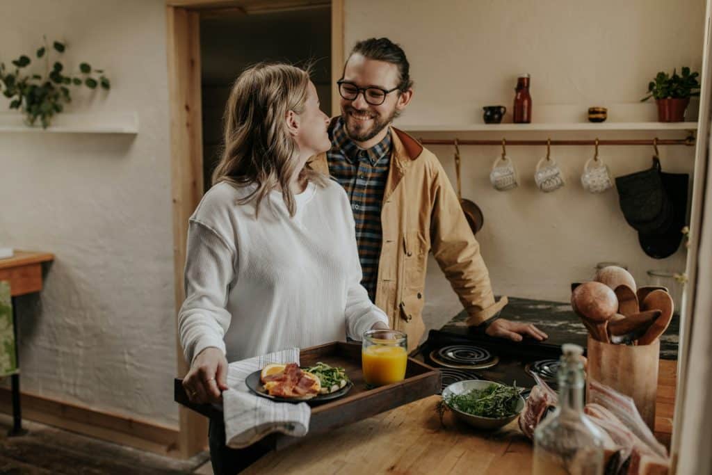 The couple is talking in the kitchen while preparing food.