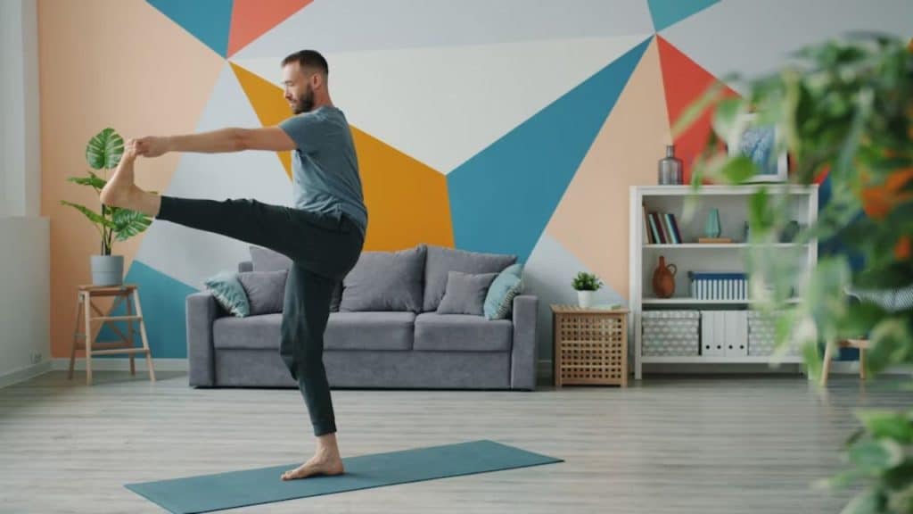 Man stretching on a yoga mat in his living room