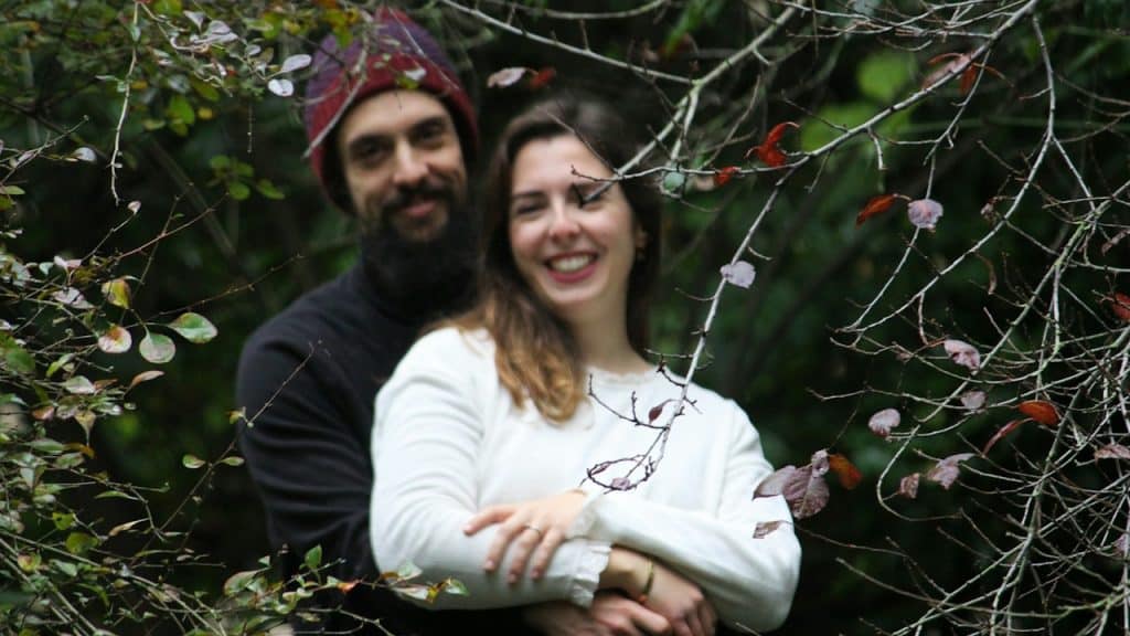 A man and a woman standing next to each other near plants.