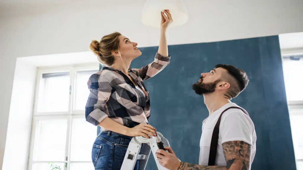 A couple changing the lightbulb at home