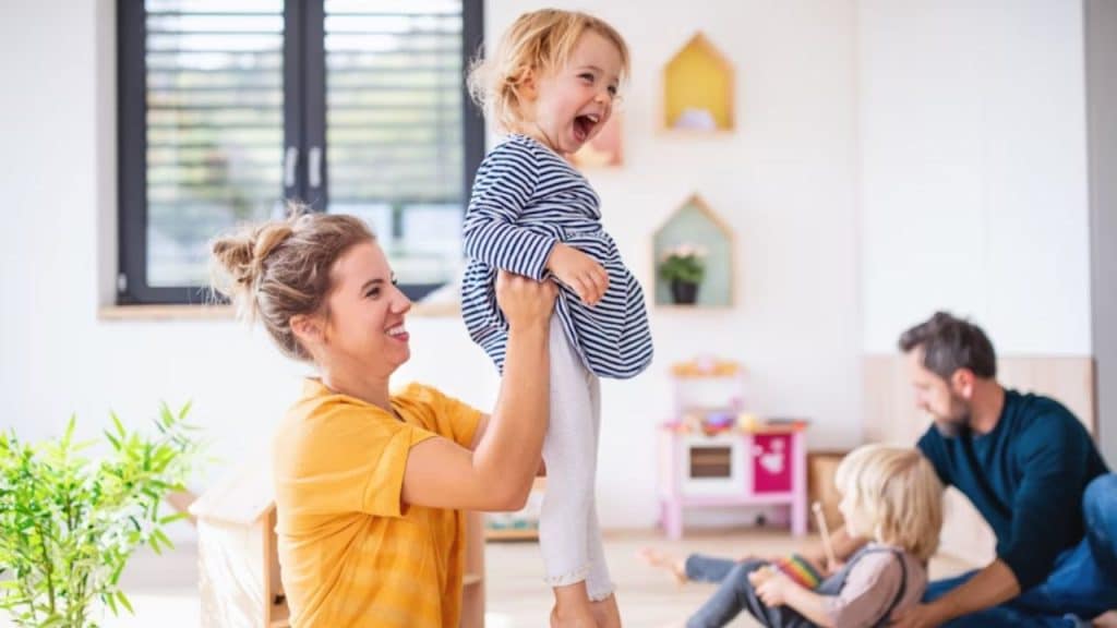 Man vacuuming while partner plays with child on the couch