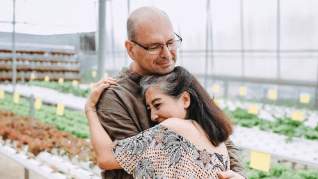 A couple hugging in a greenhouse
